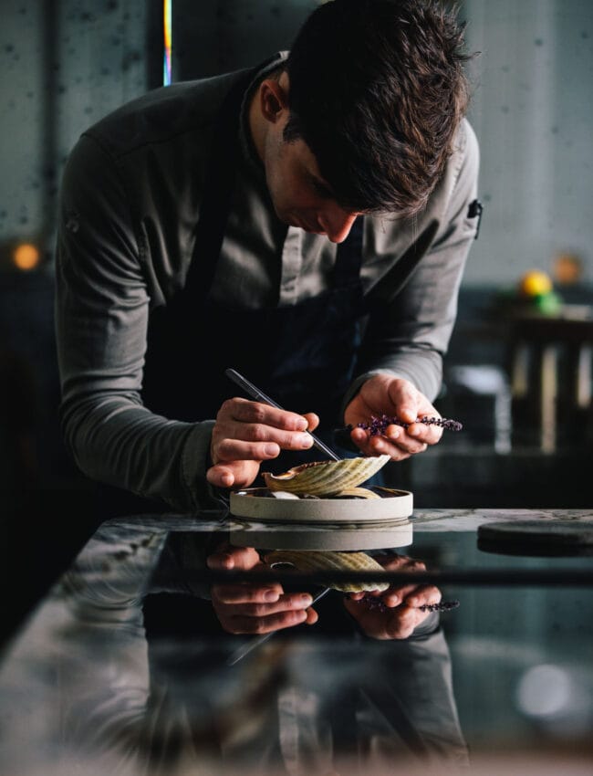 Chef Filip Hanlo working on the scallop dish at restaurant até in luxury boutique hotel The Dylan Amsterdam.