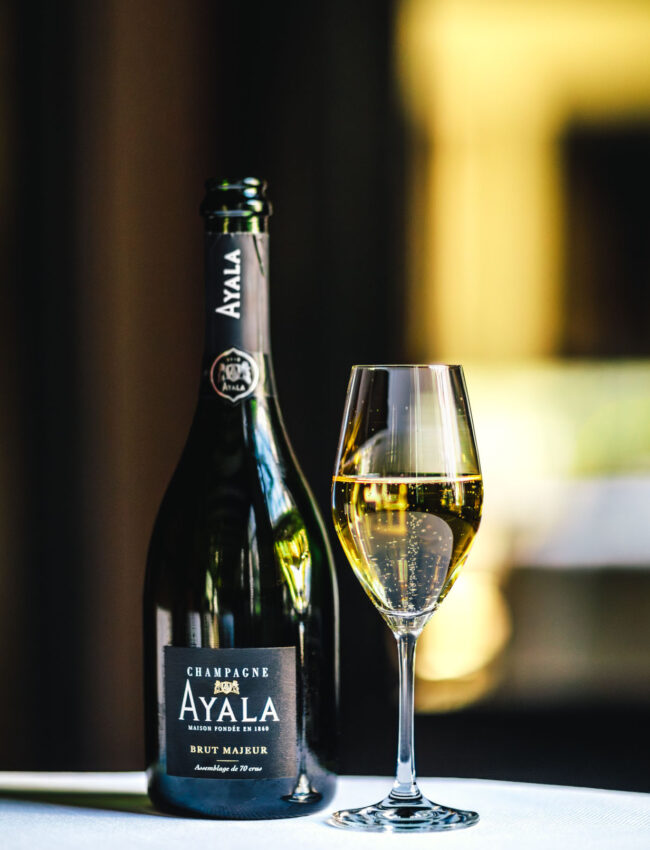 Glass of Ayala Brut Majeur Champagne and a flute glass of bubbly in Vinkeles, a restaurant which gastronomy has been awarded 2 michelin stars at luxury boutique hotel The Dylan Amsterdam, part of the Leading hotels of The World (LHW)