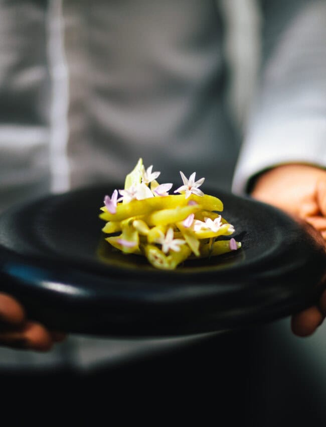 Chef of two Michelin star Restaurant Vinkeles holding a dish, located at The Dylan, part of The Leading Hotels of the World
